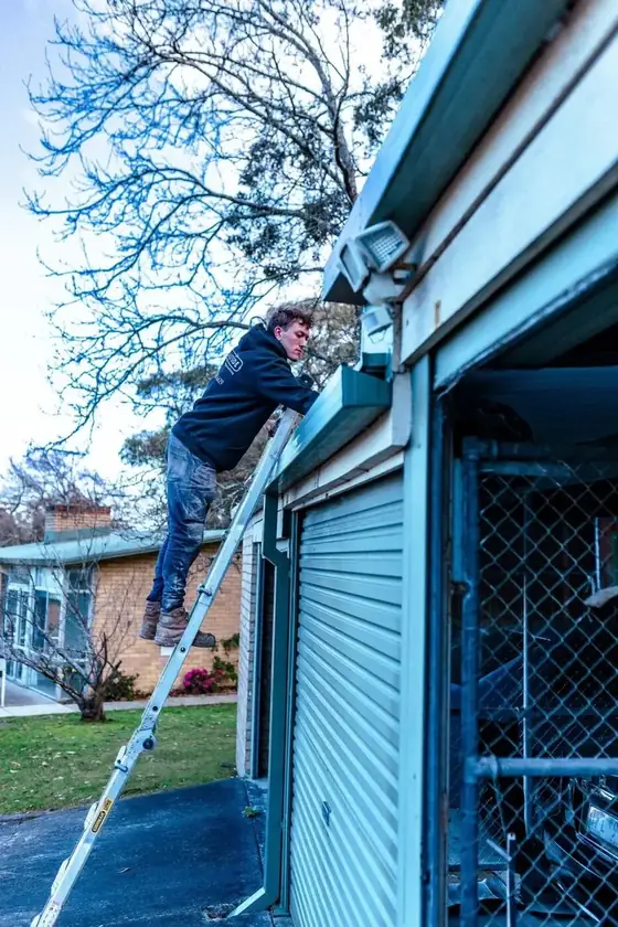 Technician working from a ladder at a building gutter